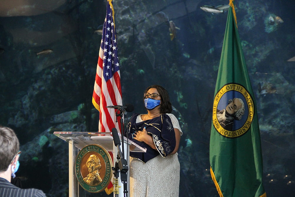 State Senator Mona Das speaking at a podium in front of the Window on Washington Waters habitat.
