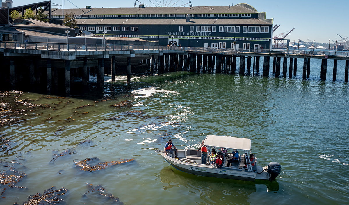 A team of research scientists on a small boat, floating on the water next to the Seattle Aquarium as they conduct underwater research using ROV Nereo.