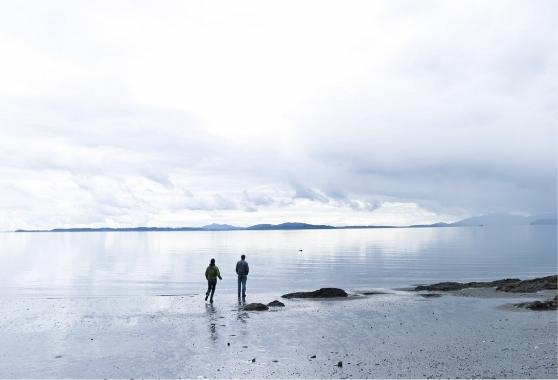 landscape image of the ocean with two people standing on the shore