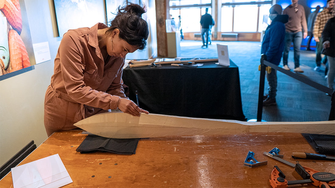 An artist carving a wooden paddle.