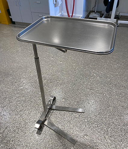 A small metal table tray attached to an adjustable metal stand.