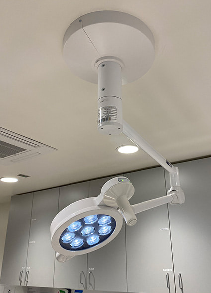 A large, adjustable examination light fixture hanging from the ceiling.