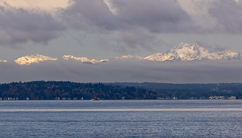Olympic Mountain range viewed across Elliot Bay on a partly cloudy day.