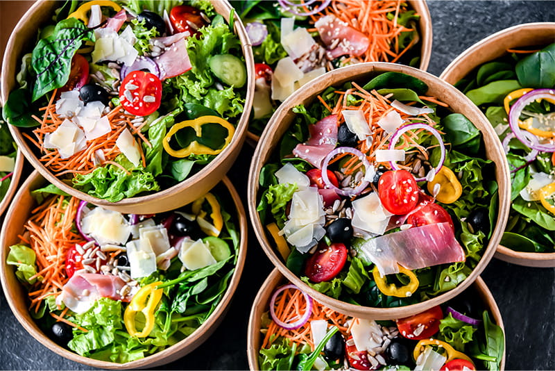 Different individual salads, each inside in sustainable bowls, on top of a table.