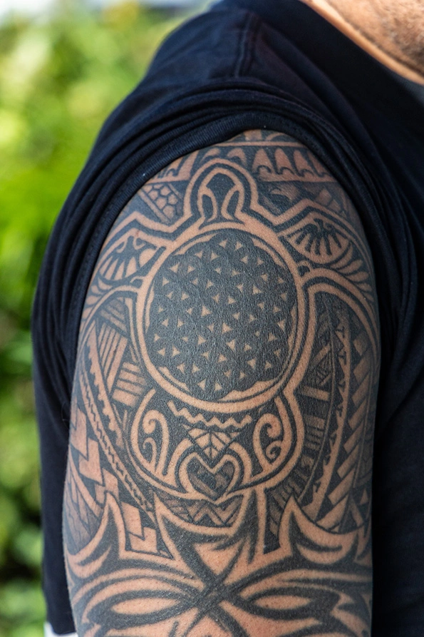 A close-up of Mike's shoulder tattoo, featuring a sea turtle with the seed of life symbol on its shell.