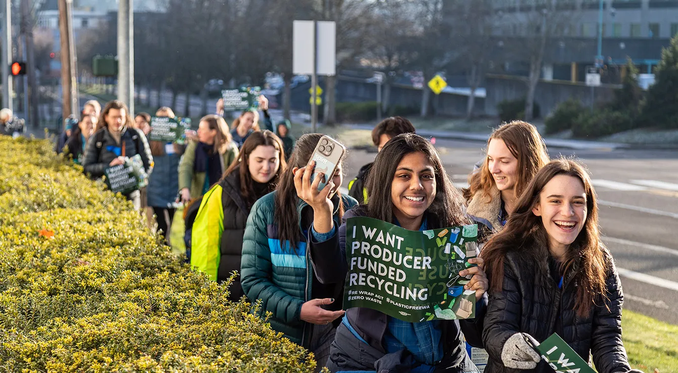 Seattle Aquarium Youth Ocean Advocates march with other Washington State residents along a street in Olympia, Washington, holding signs advocating for improved recycling programs and producer funded recycling.