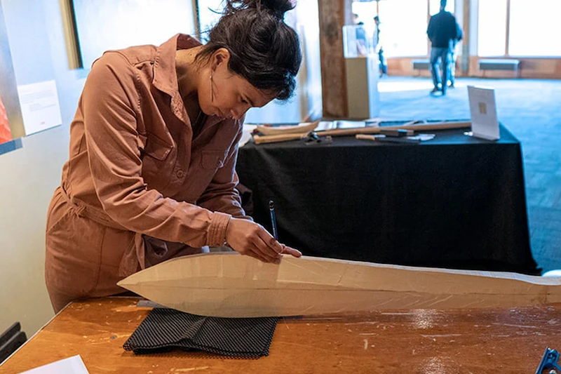 An artist creating a hand carved wooden paddle during a live demonstration at the Seattle Aquarium.