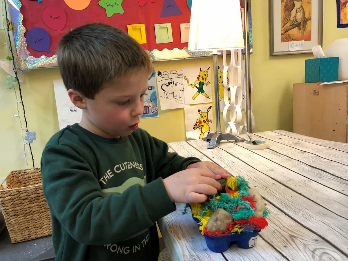 A young child constructing a coral reef out of yarn.