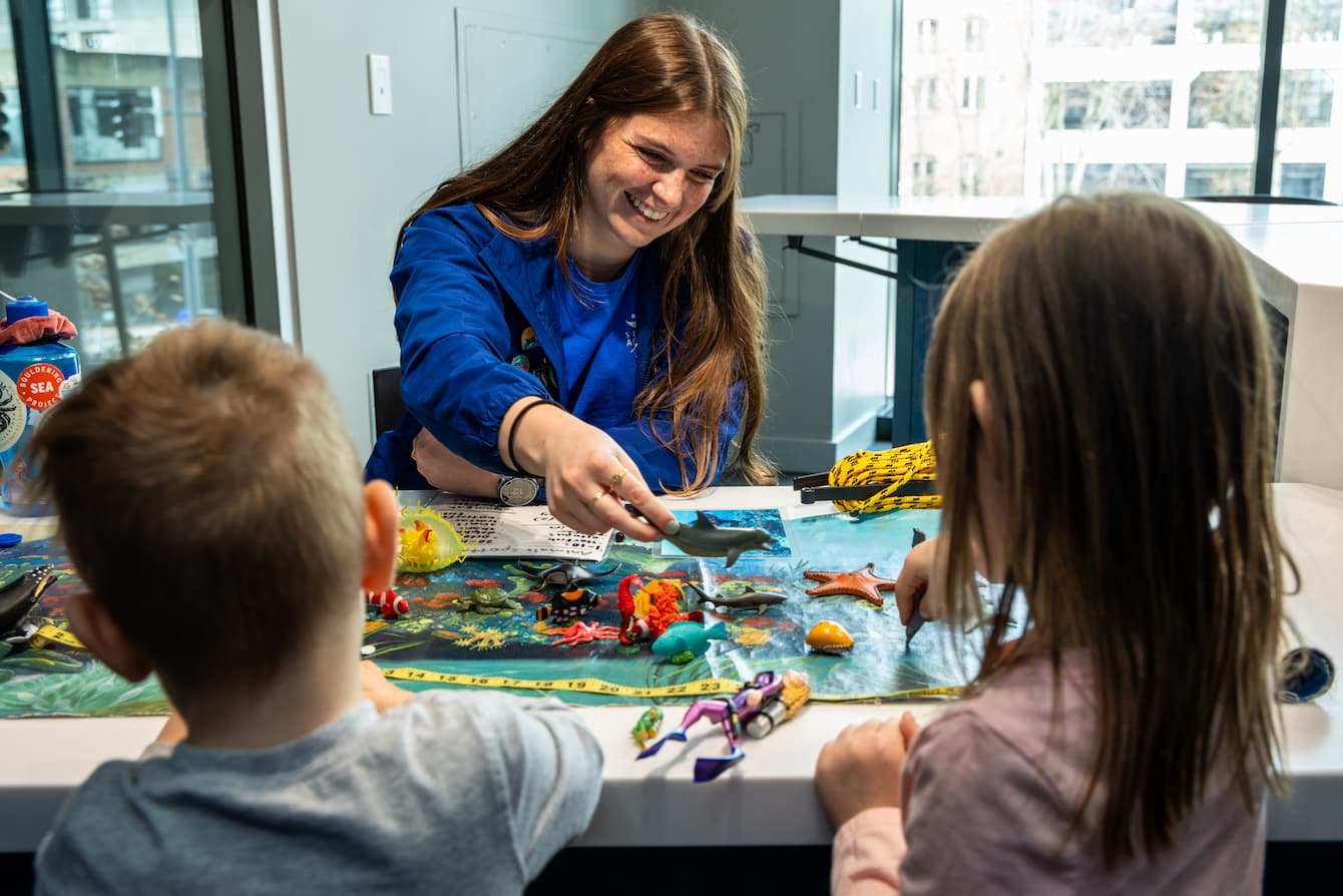 A Seattle Aquarium volunteer teaching two children at the Discovery Lab.
