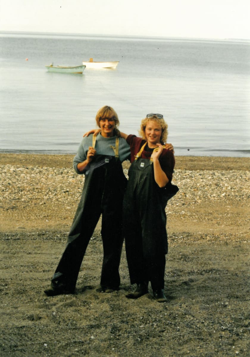A young Peggy standing on a shoreline with her arm around another woman.
