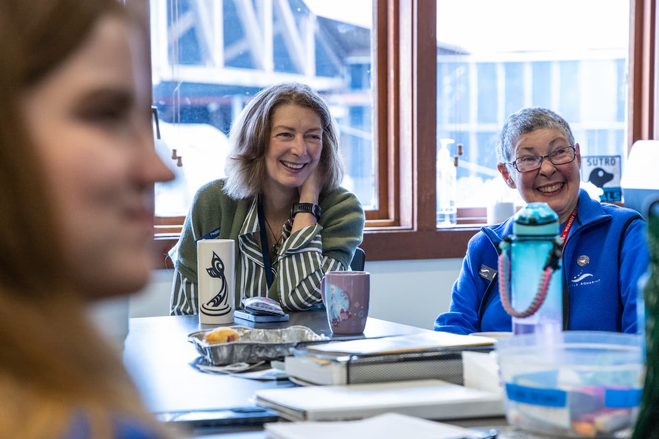 Peggy sitting at a table with Aquarium volunteers.