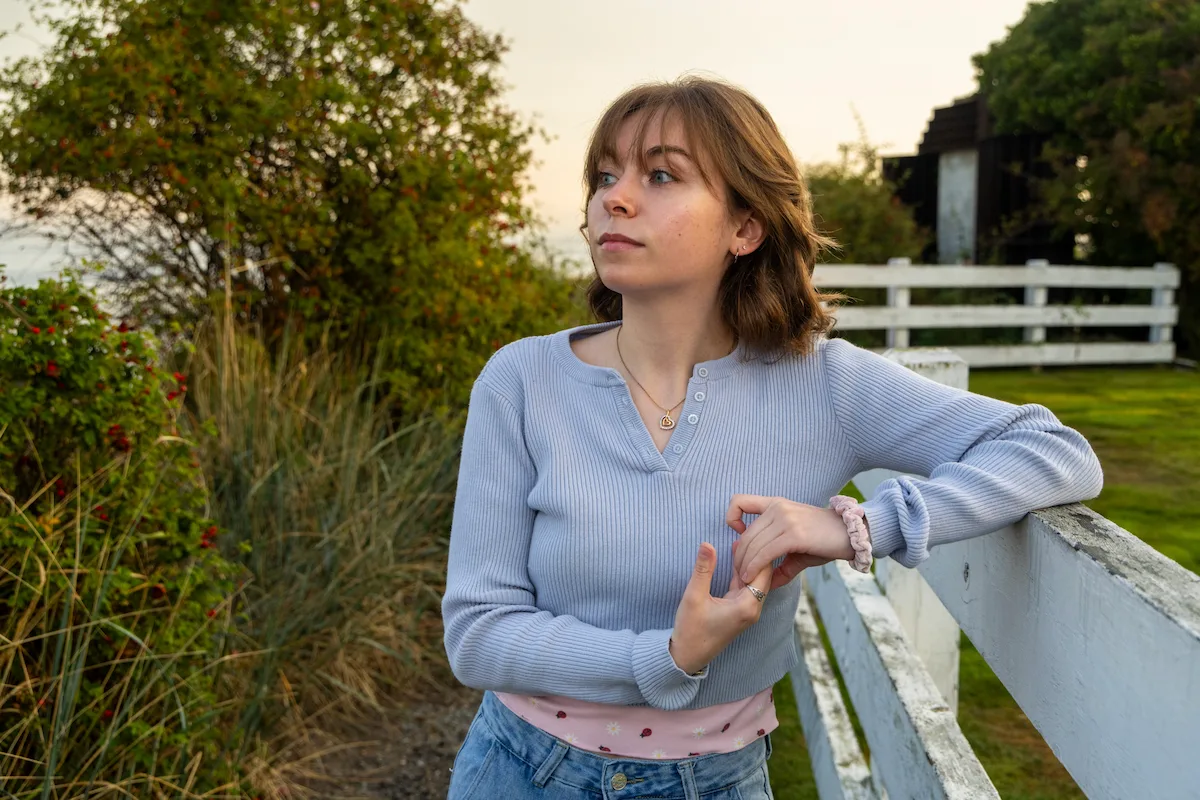 Molly leaning against a fence, surrounded by trees.