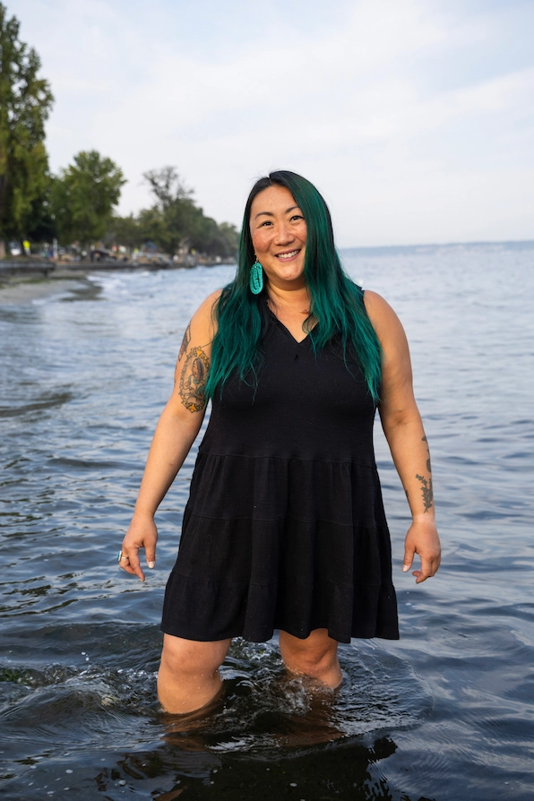 Chelsea wearing a black dress and standing in the water.
