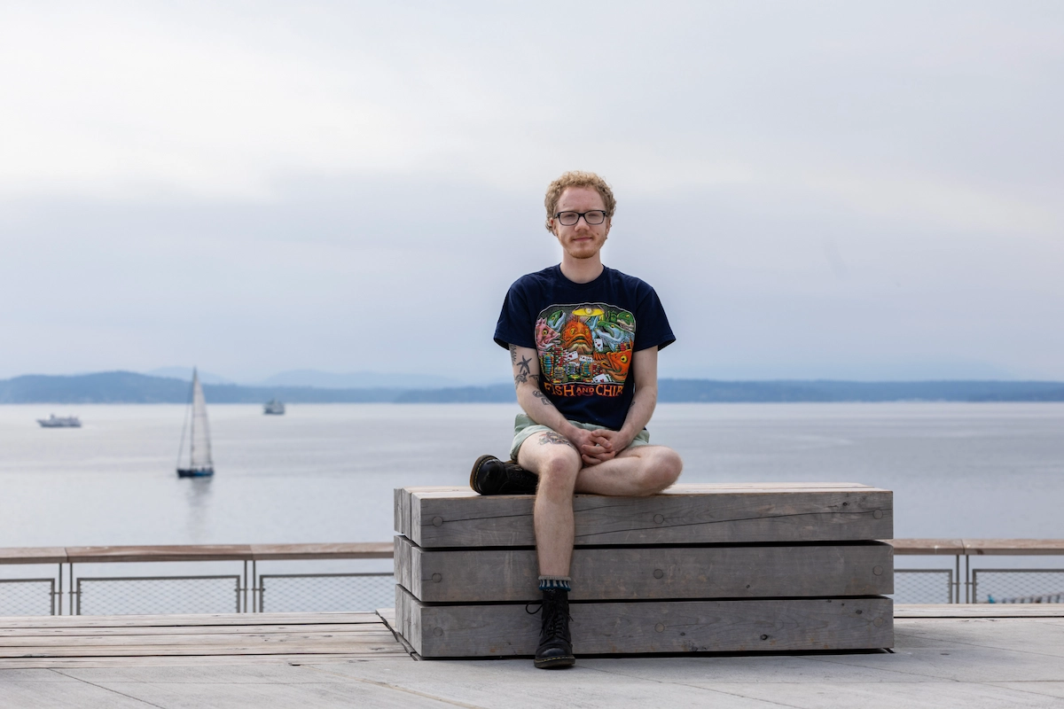 Chris wearing a black shirt and sitting in front of the water.