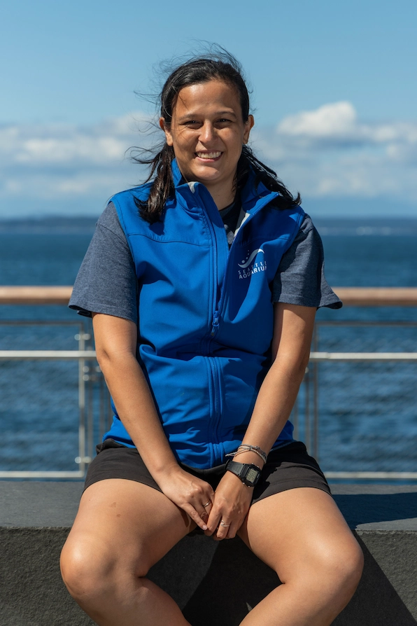 Taylor wearing a blue vest and sitting in front of the water.