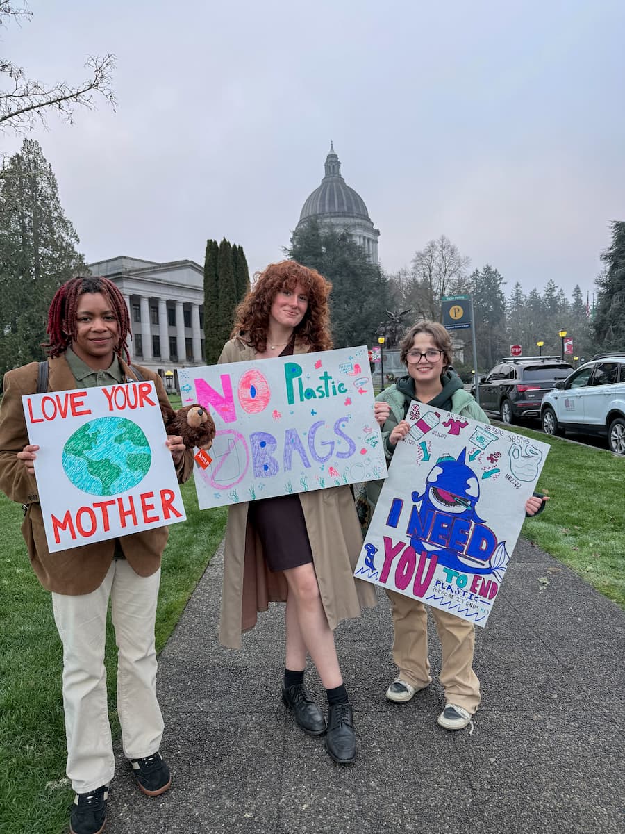 Three Youth Ocean Advocates holding handmade signs calling for less plastic.