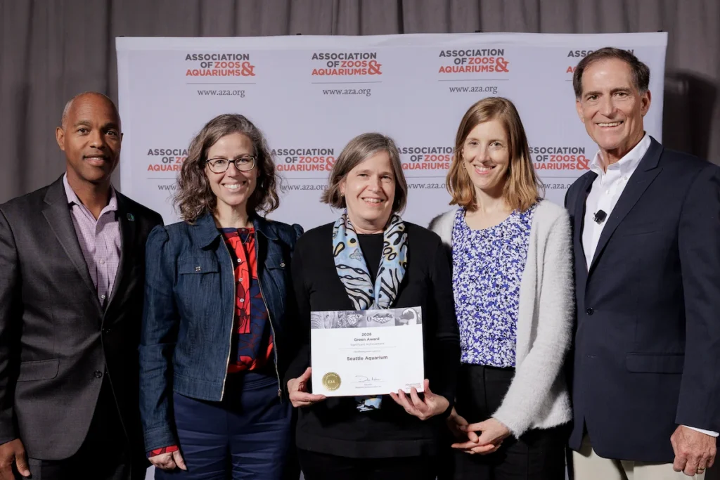 Seattle Aquarium Board Chair Charles E. Wright, Jr., Aquarium President & CEO Meg McCann, Aquarium Senior Director of Capital Projects Susan Bullerdick, Aquarium VP of Conservation Programs and Partnerships Nora Nickum, and AZA President & CEO Dan Ashe at the AZA award ceremony, posing for a photo with the award the Aquarium was presented.