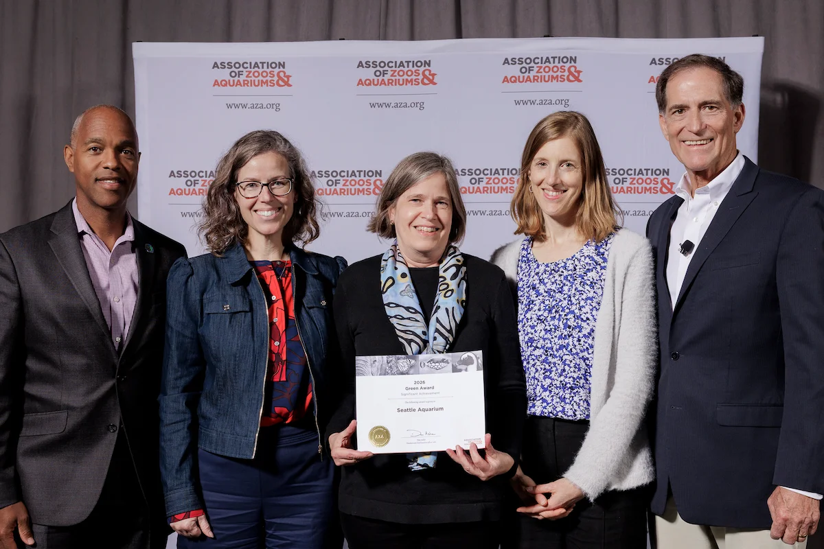 Seattle Aquarium Board Chair Charles E. Wright, Jr., Aquarium President & CEO Meg McCann, Aquarium Senior Director of Capital Projects Susan Bullerdick, Aquarium VP of Conservation Programs and Partnerships Nora Nickum, and AZA President & CEO Dan Ashe at the AZA award ceremony, posing for a photo with the award the Aquarium was presented.